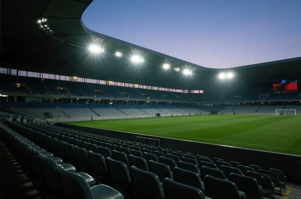 An atmospheric view of a modern sports stadium at dusk with glowing floodlights